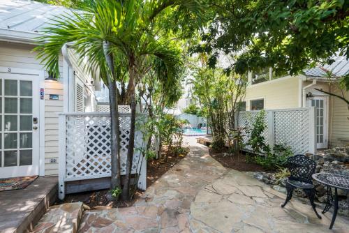 a patio with a fence and palm trees in front of a house at Sunset Suite Colony in Key West