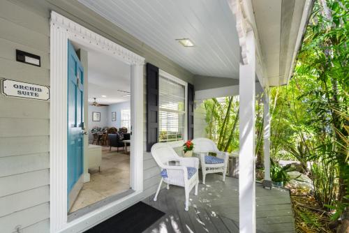a front porch with white chairs and a blue door at Orchid Suite in Key West