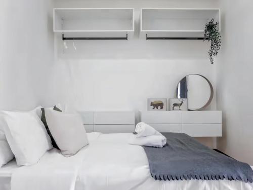 a white bed with white pillows and a mirror at Beacon Executive Suite in George Town