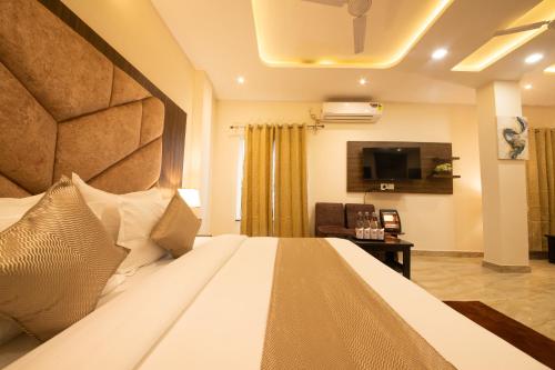 a hotel room with a bed and a television at Perfectstayz Value Dhruv Nanda near Haridwar Railway Station in Haridwār