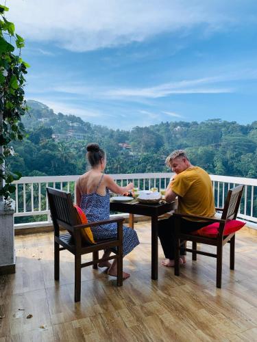 a man and a woman sitting at a table on a balcony at The Chocolate Factory House, Kandy- exclusive private apartment in Kandy