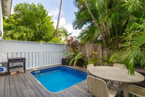 Una pequeña piscina en una terraza de madera con mesa y sillas. en A Windsong Delight, en Key West