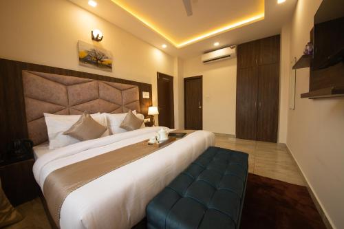 a hotel room with a large bed with a blue bench at Perfectstayz Value Dhruv Nanda near Haridwar Railway Station in Haridwār