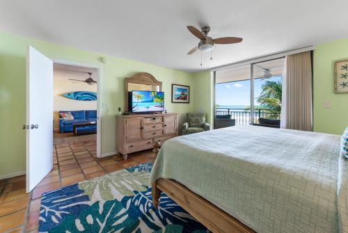 a bedroom with a bed and a television and a balcony at Beach Club Oasis 304 in Key West
