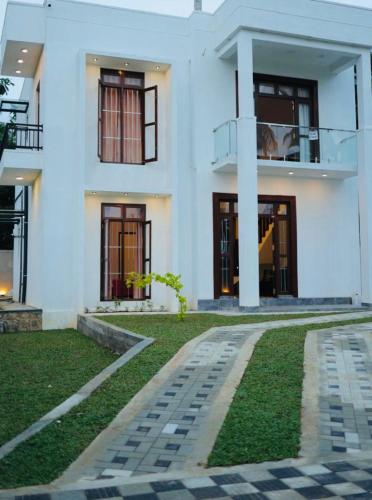a white house with a walkway in front of it at Hide Hiriketiya Villa in Dickwella