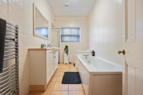 a white bathroom with a sink and a tub at HILLTOP PLACE SUITES 4 Bedrooms near PEAK DISTRICT in Killamarsh