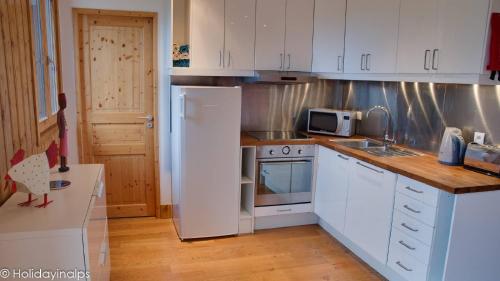 une cuisine avec des armoires blanches et un réfrigérateur blanc dans l'établissement L'Ourse 10 Duplex Apartment, à Saint-Gervais-les-Bains