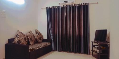 a living room with a couch in front of a curtain at candolim Neha 1bhk apartments in Bardez