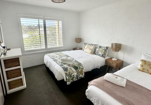 a bedroom with two beds and a window at Bermagui Stays - 2 bedroom Apartment - Amazing views & location in Bermagui