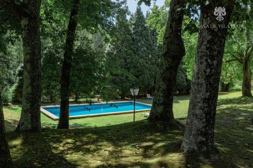a swimming pool in the middle of a park with trees at Casa de Vila Flor in Grijó