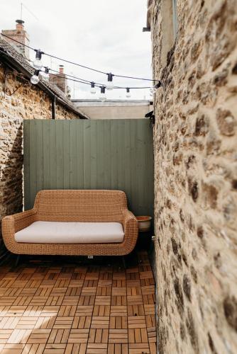 a wicker couch sitting on a patio next to a wall at Stunning 2BD in the Heart of Malmesbury! in Malmesbury