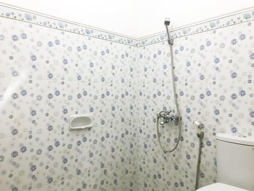 a bathroom with a shower with blue flowers on the wall at Villa Bunga Guest House RedPartner in Malang