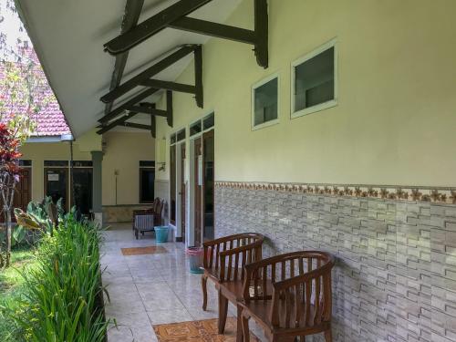 a patio with two wooden benches next to a building at Villa Bunga Guest House RedPartner in Malang