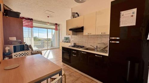 La cuisine est équipée d'un réfrigérateur noir et d'un évier. dans l'établissement Appartement 2 pièces PORT LA NOUVELLE PN430-027, à Port-la-Nouvelle