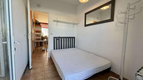 une petite chambre avec un lit et un miroir dans l'établissement Appartement 2 pièces PORT LA NOUVELLE PN430-027, à Port-la-Nouvelle