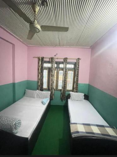 ポカラにあるTripti guest houseのベッド2台 緑とピンクの部屋