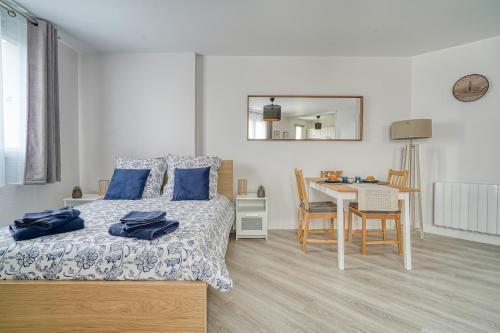 - une chambre avec un lit doté d'oreillers bleus et d'une table dans l'établissement Logement Jules, Évry-Courcouronnes