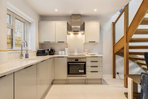 a kitchen with white cabinets and a staircase at The Little House in Oxwich in Oxwich