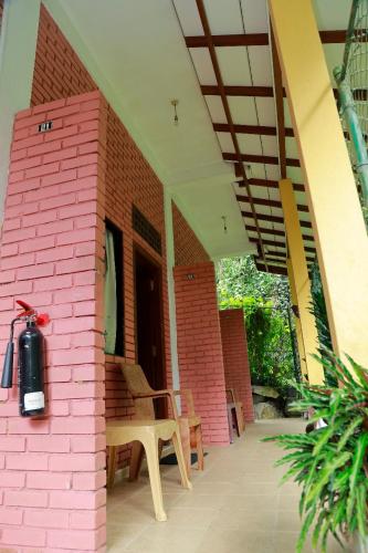 a pink brick building with a bench on a patio at Star Rain Tour Inn in Ratnapura