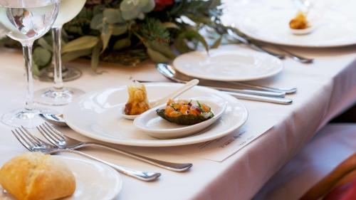 a table with plates of food and forks and glasses at Radisson Blu 1882 Hotel, Barcelona Sagrada Familia in Barcelona