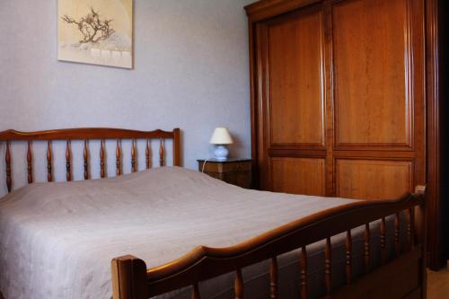 a bedroom with a bed and a wooden cabinet at Les Louchardes in La Rochepot
