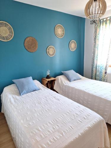 two beds in a room with a blue wall at Les Louchardes in La Rochepot
