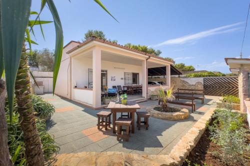 a patio with picnic tables and benches in front of a house at White Sand Private Villa Near The Sea, Wifi in Torre Squillace