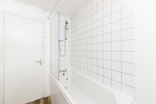 a white tiled bathroom with a bath tub at Printworks Building City Centre Penthouse 5 Bedrooms Sleeps 14 in Gloucester