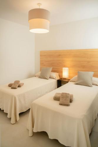 two beds in a room with white walls at Panasco Suites in Arrecife