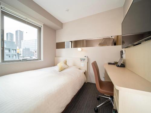 a hotel room with a bed and a desk and a window at Super Hotel Premier Musashi Kosugi Ekimae in Kawasaki