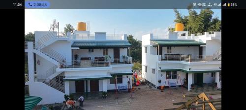a large white building with people standing in front of it at Rithu's Inn in Yelagiri