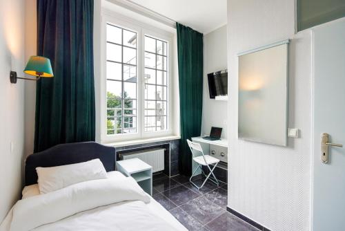 a bedroom with a bed and a desk and a window at Hotelzimmer in Düsseldorf 2 Heidelberger Hof in Düsseldorf