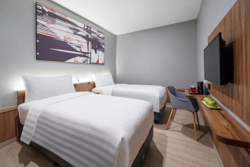 a hotel room with two beds and a flat screen tv at Hotel Neo Plus Airport Jakarta in Tangerang
