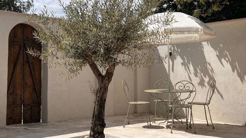 une table, des chaises et un arbre en face d'un bâtiment dans l'établissement NOUVEAU ! Le Ptit Brou, à Bourg-en-Bresse