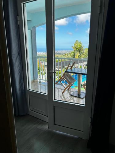 a door to a balcony with a view of the ocean at Hôtel Le Soleil Couchant in Saint-Pierre