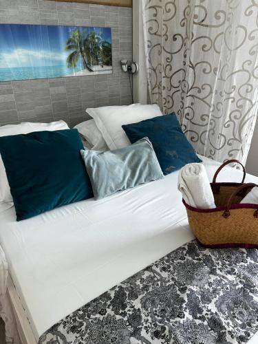 a large white bed with blue pillows and a basket at Hôtel Le Soleil Couchant in Saint-Pierre