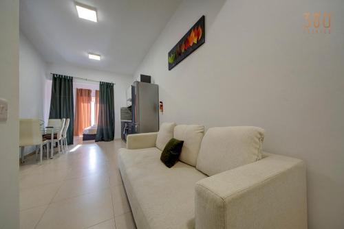 a living room with a white couch and a kitchen at Cozy Studio home with Stunning Mosta Dome Views by 360 Estates in Mosta
