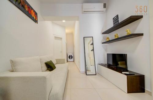 a living room with a white couch and a tv at Cozy Studio home with Stunning Mosta Dome Views by 360 Estates in Mosta
