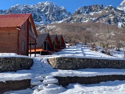 a row of cabins in the snow with mountains in the background at Guest House Astrit Villi in Theth