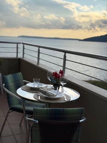 een tafel met 2 wijnglazen en bloemen op een balkon bij Savina apartment Herceg Novi in Herceg-Novi