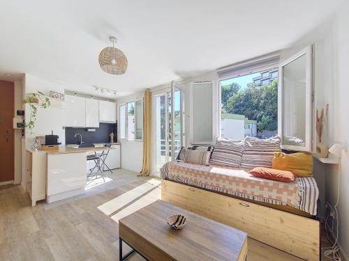 Cet appartement comprend une chambre avec un lit, une grande fenêtre et une cuisine. dans l'établissement Studio toit terrasse vue mer Sea View, à Nice