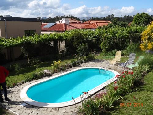 a swimming pool in a yard with chairs and flowers at Quinta das Delicias in São Tiaguinho