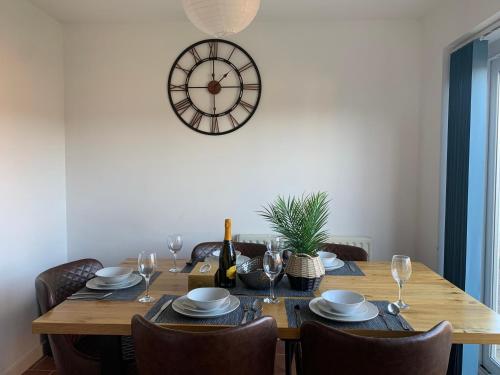 a dining room table with chairs and a clock on the wall at Montrose House in Swindon