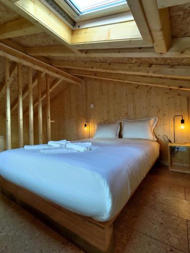 a large white bed in a room with a ceiling at 1 minute from beach - Baleal Wood Cabin in Baleal