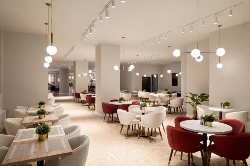a restaurant with white tables and red chairs at Ramada by Wyndham Bucharest Otopeni Airport in Otopeni