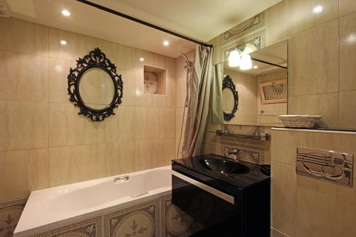 une salle de bain avec un lavabo, une baignoire et un miroir dans l'établissement Appartement spacieux au cœur de Paris 75 m² avec vue sur la ville, à Paris