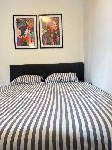 a bed with striped sheets and two pictures on the wall at visit Brussels city in Brussels