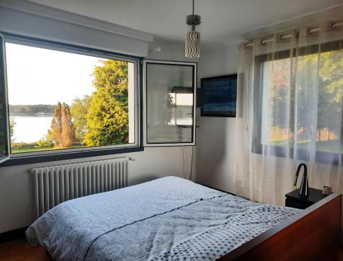 une chambre avec un lit et deux grandes fenêtres dans l'établissement Maison au bord de l'eau, à Baden