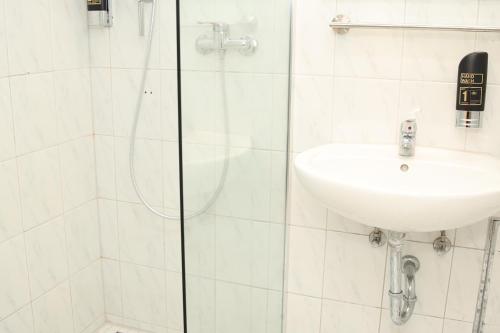 a white bathroom with a sink and a shower at Hotel Hafez in Bad Salzuflen