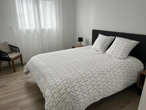 une chambre avec un lit avec une couette noire et blanche dans l'établissement Villa L'Evasion, neuve, 4 chambres, 8pers, piscine chauffée, à Andernos-les-Bains